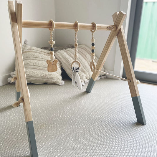Baby using the 'Baby Play Gym in Grey colour' by Four Little Monkeys, showcasing the modern design with a splash of grey and 3 removable hanging toys.
