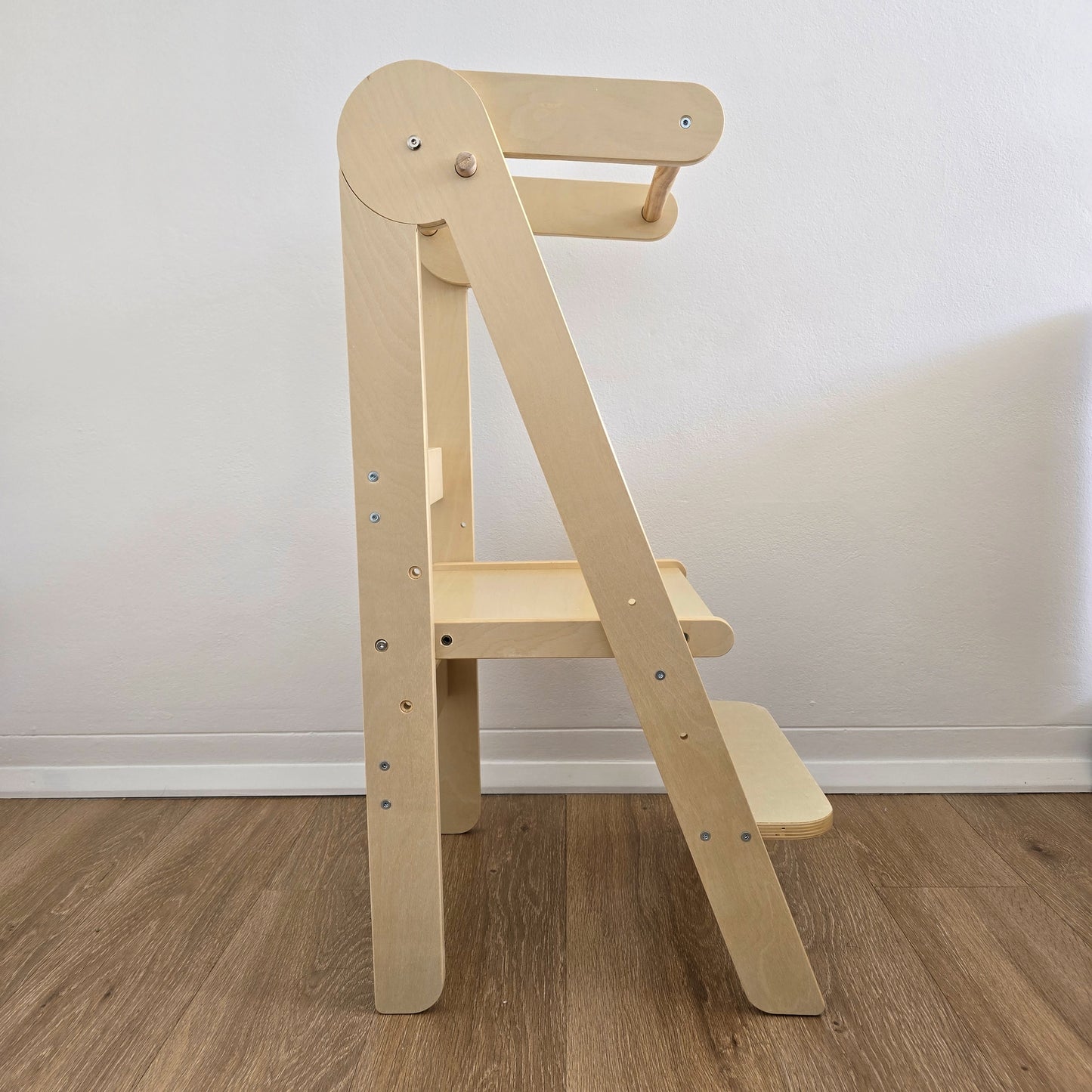 Side view of the Four Little Monkeys Natural Adjustable Foldable Learning Tower demonstrating its slim profile.