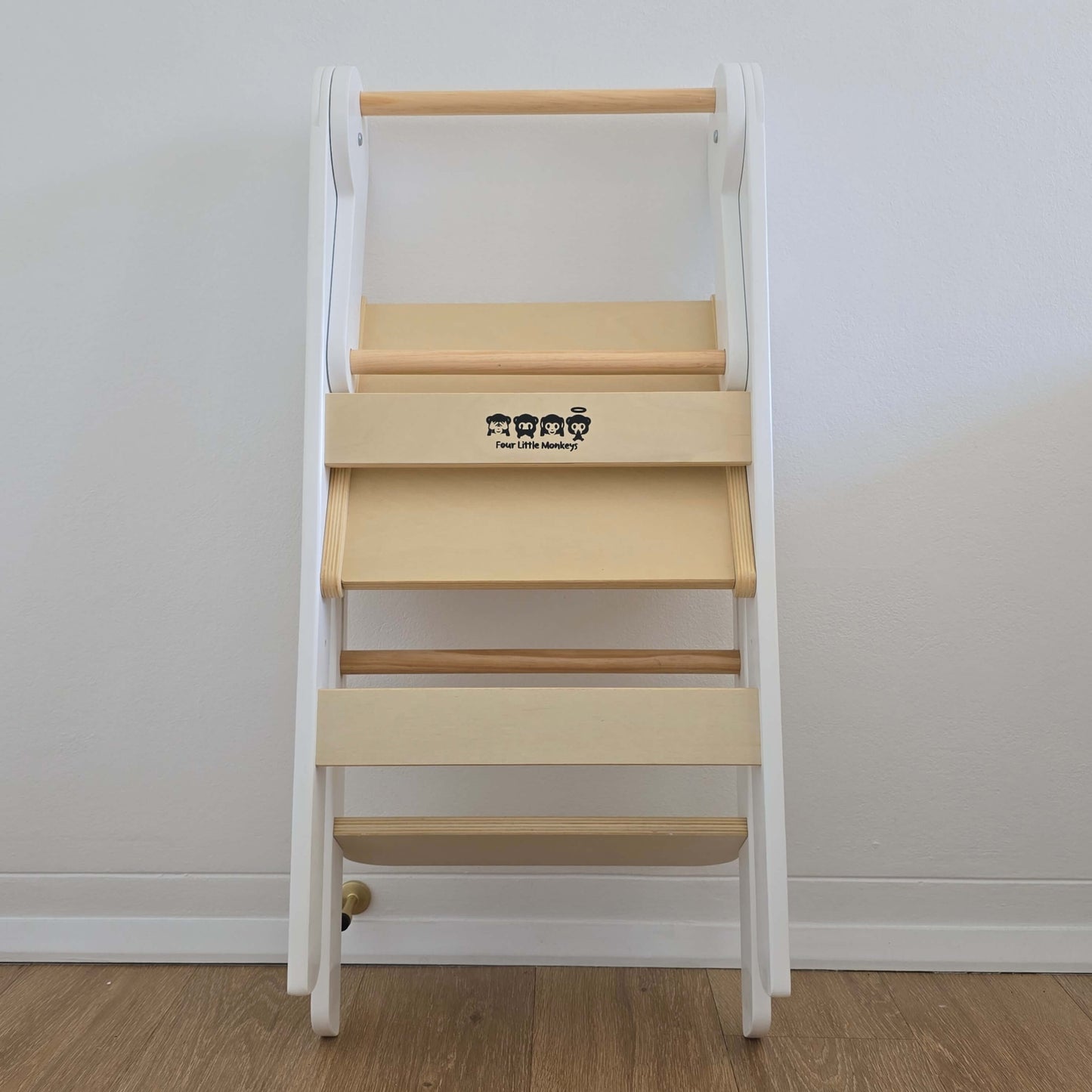 Four Little Monkeys White Adjustable Foldable Learning Tower folded up and leaning against a wall for easy storage.