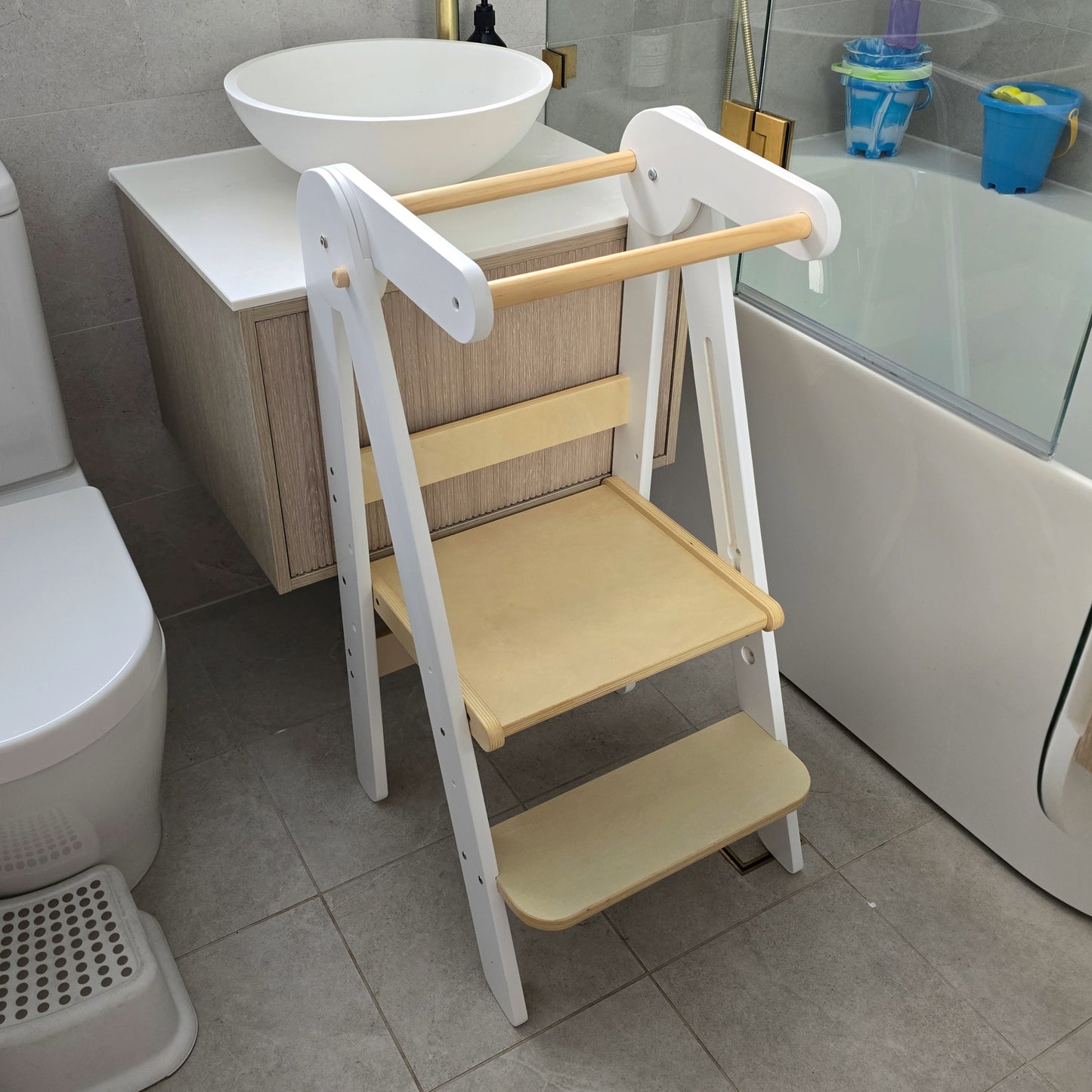 Four Little Monkeys White Adjustable Foldable Learning Tower folded up and leaning against a wall for easy storage.