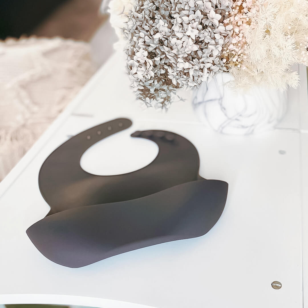 Image of a grey silicone bib with the brand name 'Four Little Monkeys'