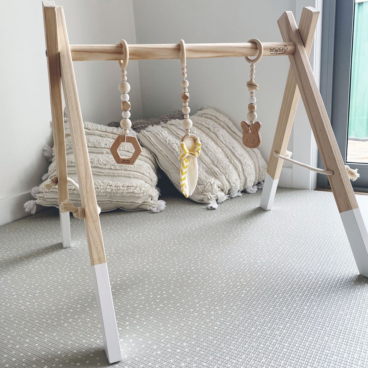 Baby playing under the 'Baby Play Gym in White colour' by Four Little Monkeys, featuring a modern design with a white highlight and 3 removable hanging toys.