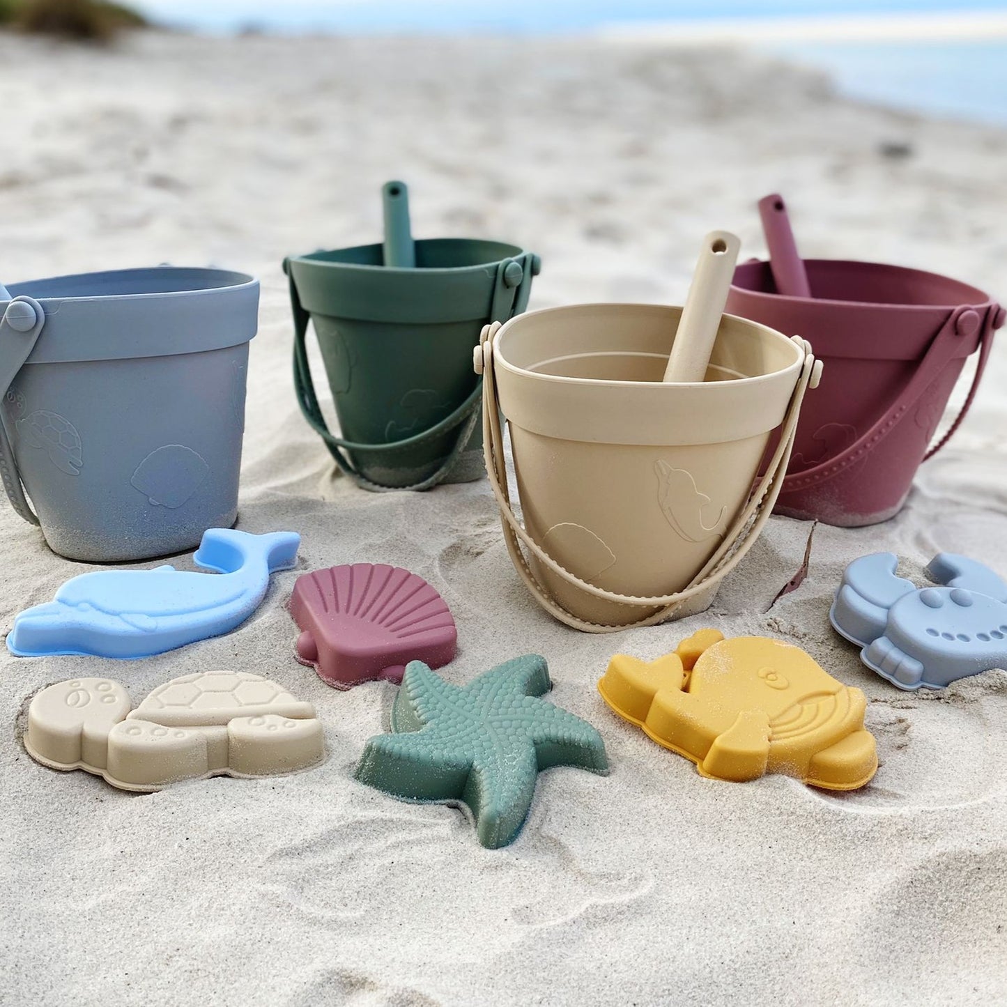 Assorted color options of the Premium Silicone Beach Set for kids on display, featuring durable buckets, moulds, and shovels in various vibrant shades, all BPA-free, dishwasher safe, and unbreakable, perfect for fun and safe playtime at the beach