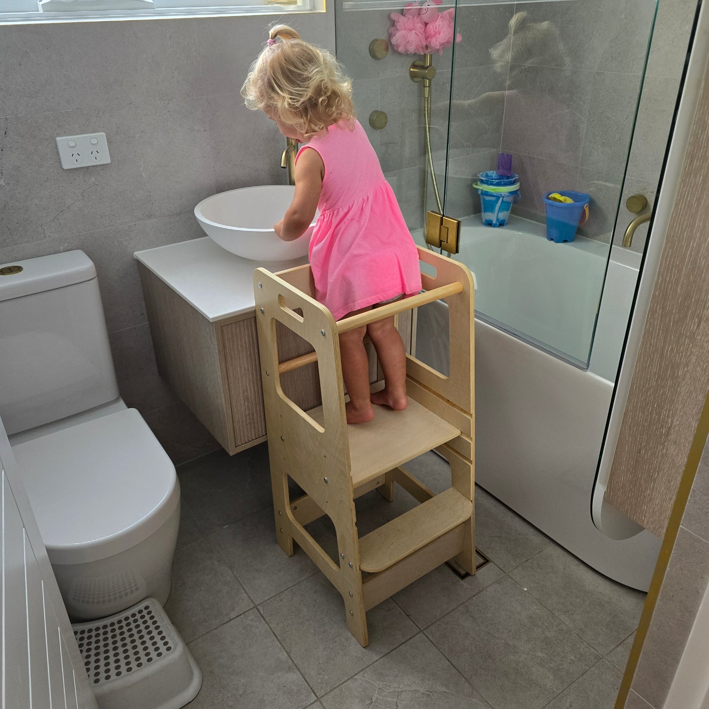 Little girl on the Natural Adjustable Learning Tower at a bathroom sink washing her hands.