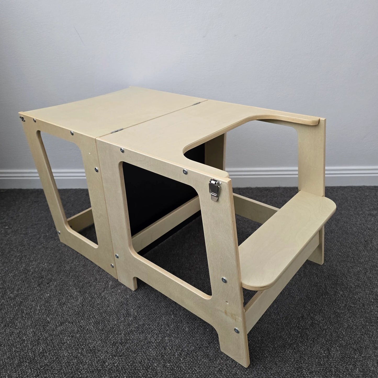 The wooden convertible learning tower transformed into a table configuration with a matching small bench, both in a natural finish.