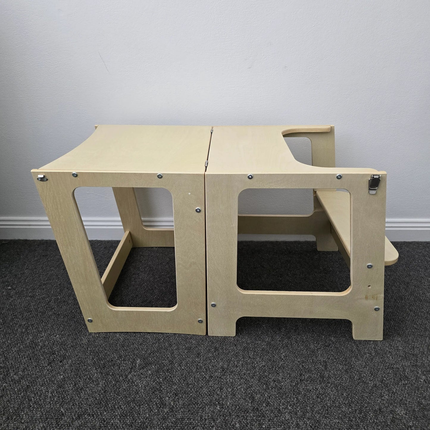 Side profile of the wooden convertible learning tower set up as a table with an attached bench, in a natural finish.