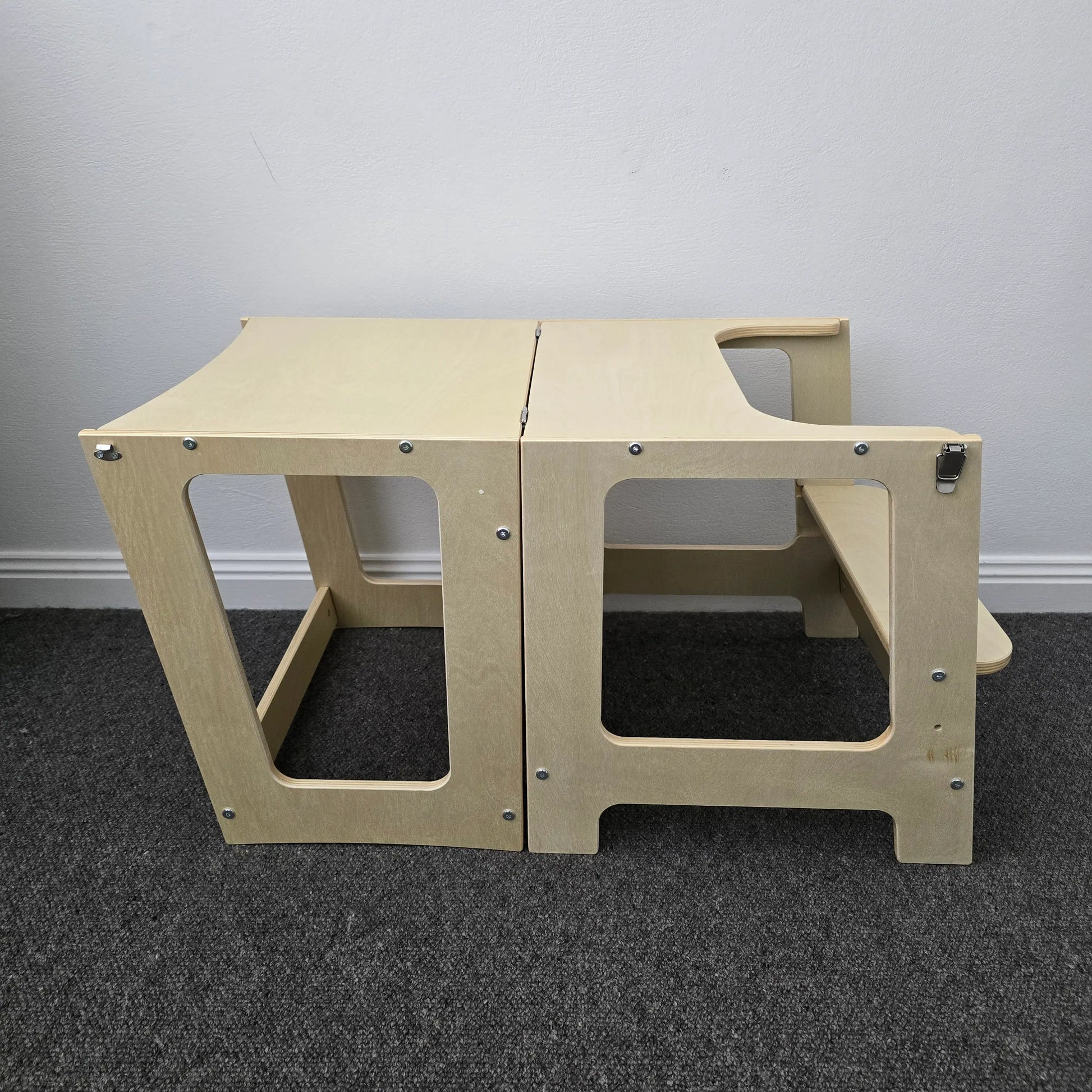 Side profile of the wooden convertible learning tower set up as a table with an attached bench, in a natural finish.