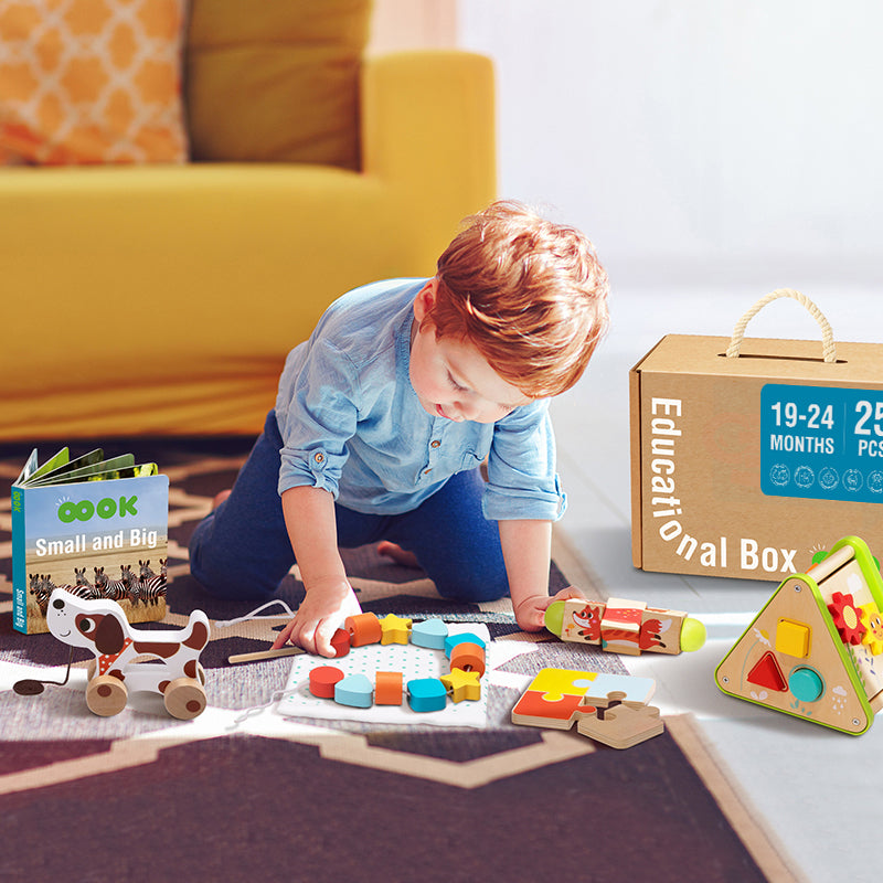 A joyful toddler engaging with the Monkey Play and Learn Box, for ages 19-24 months, exploring a variety of colourful Montessori-inspired toys like a puzzle, pull-along dog, and shape sorter.